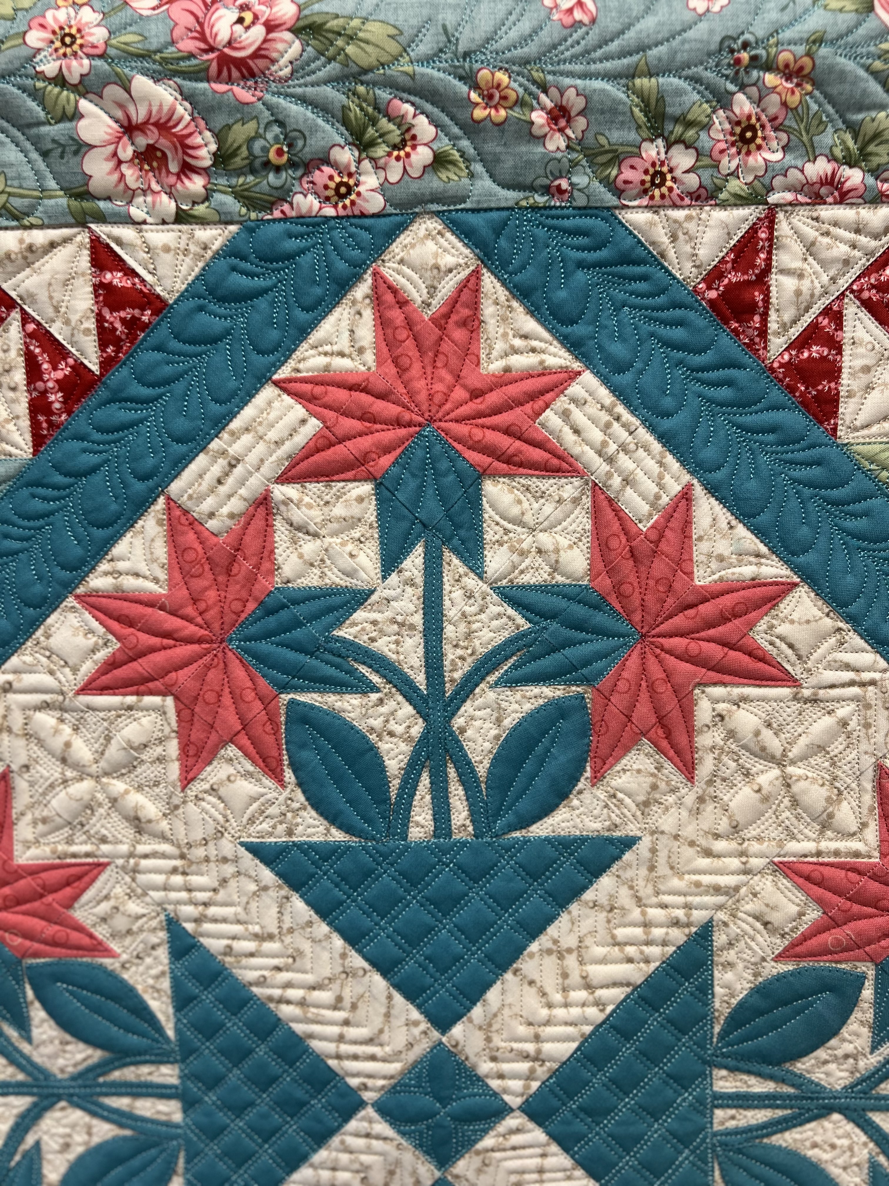 Close view of hand-guided quilting stitches worked into a pieced quilt