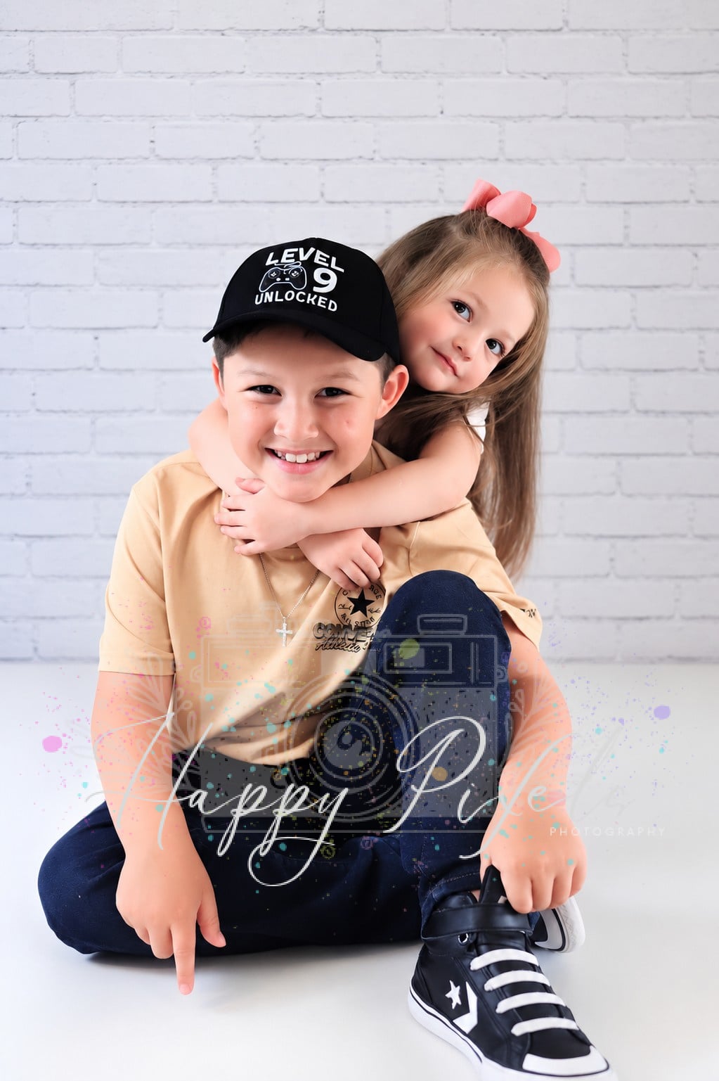 Brother and sister photographed against a white brick wall