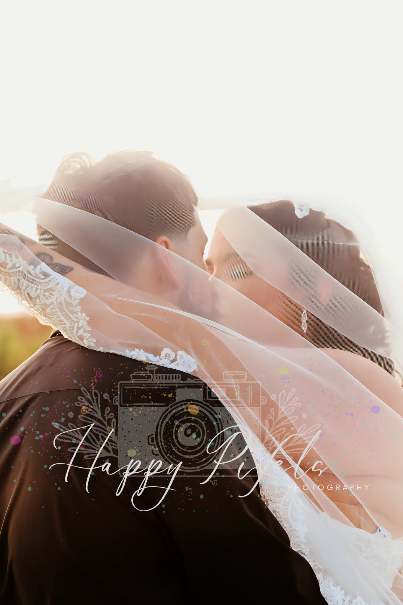 Couple photographed beneath a bridal veil