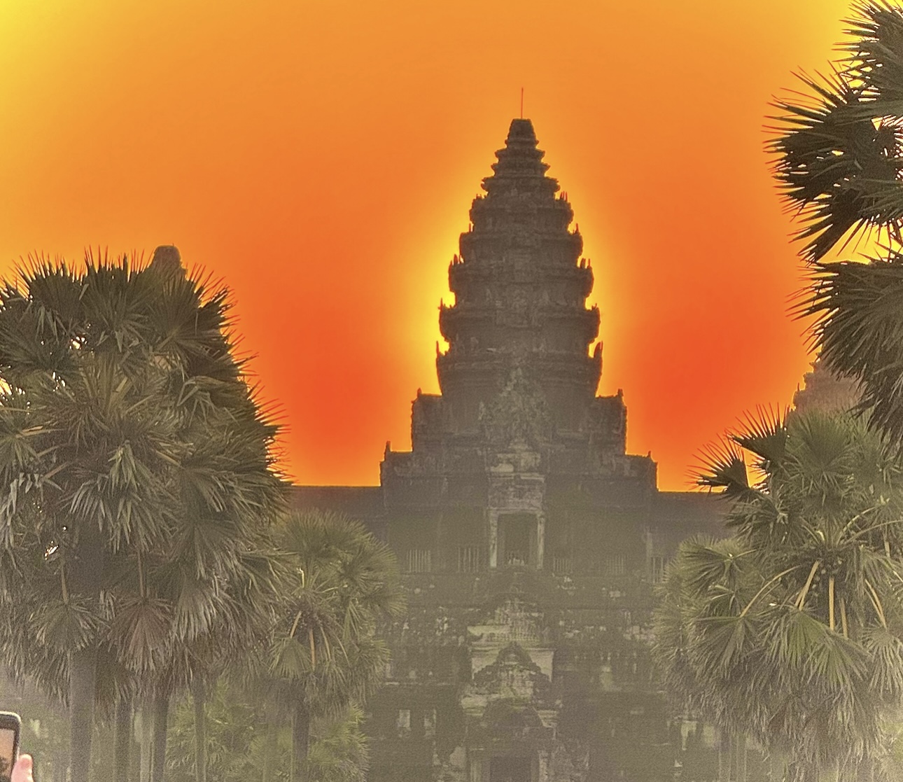 Monk seated before Angkor Wat at sunset