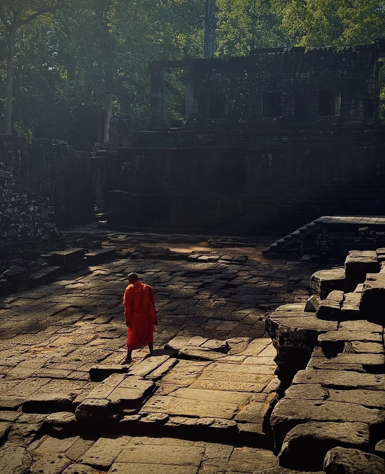 Monk in saffron robes walking through temple ruins