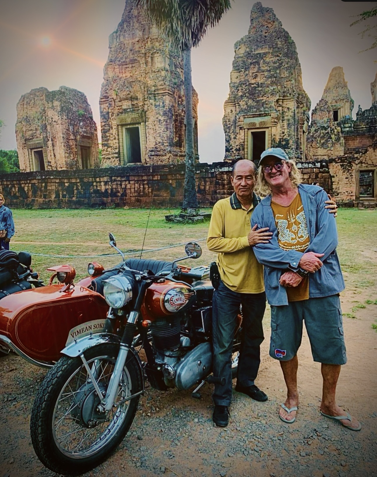 Guests posing with a vintage motorcycle in front of a temple gate