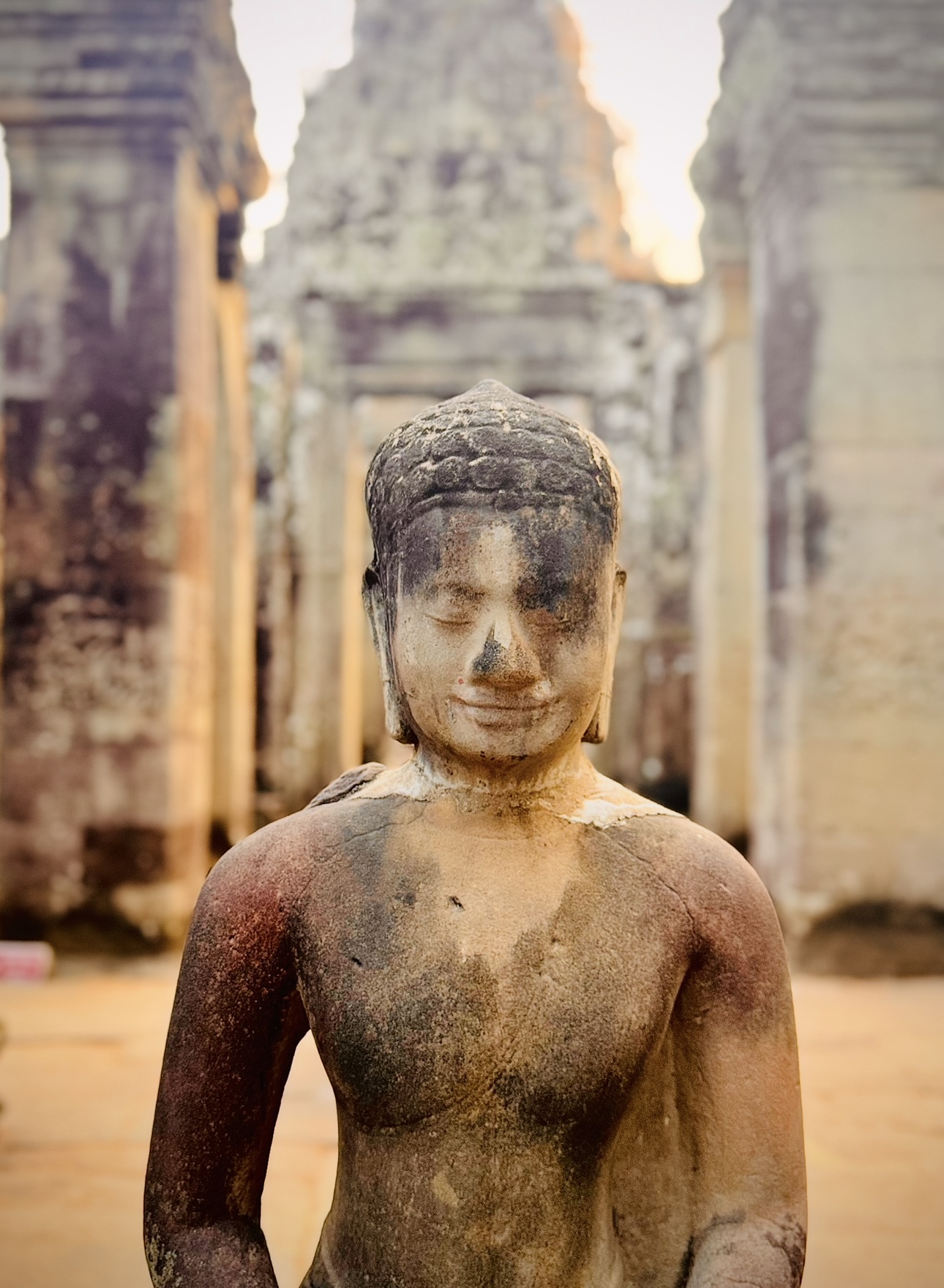 Weathered stone statue inside an Angkor temple
