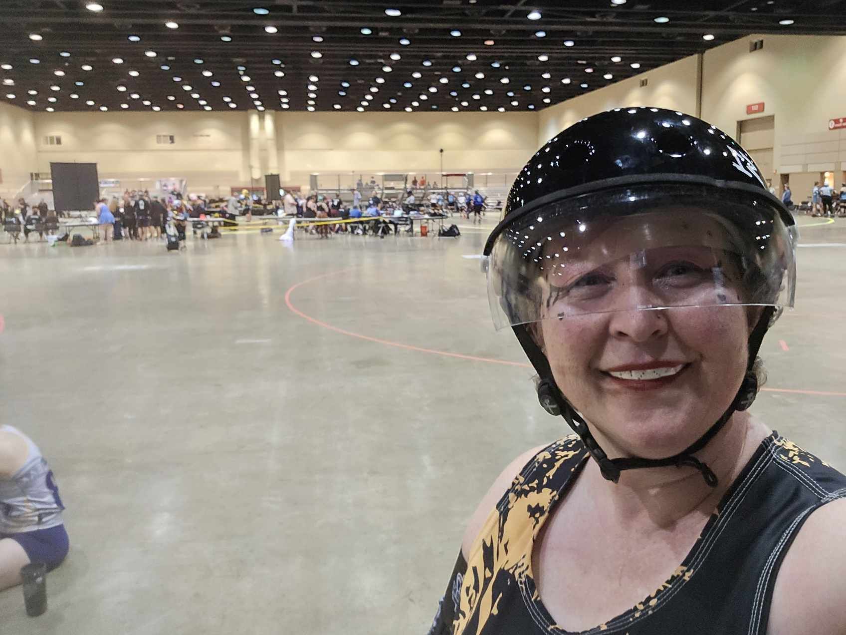 Tonya wearing roller derby safety equipment at an indoor venue
