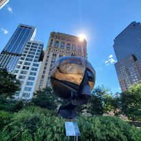 Outdoor spherical sculpture framed by city buildings